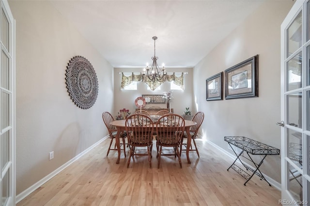dining space with baseboards, light wood-style flooring, and a chandelier
