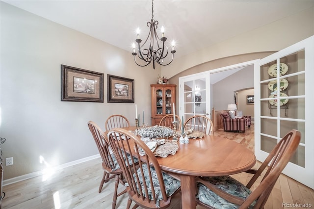dining room featuring an inviting chandelier, baseboards, french doors, and light wood-type flooring