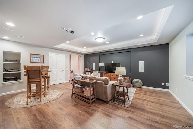 living area featuring recessed lighting, baseboards, wood finished floors, and a tray ceiling