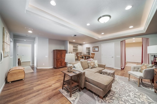 living area with recessed lighting, a tray ceiling, baseboards, and light wood finished floors