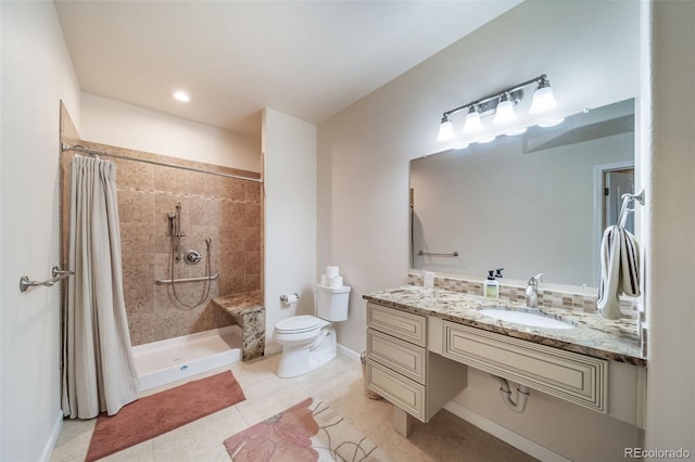 bathroom with vanity, toilet, baseboards, tile patterned floors, and a tile shower