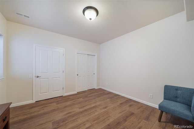 unfurnished room featuring baseboards, wood finished floors, and visible vents