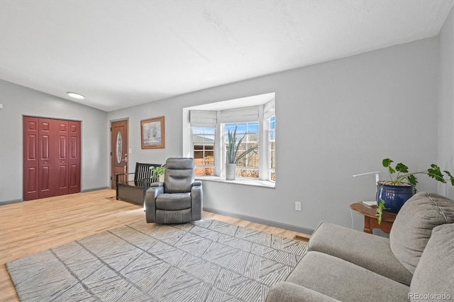 living area featuring vaulted ceiling, wood finished floors, and baseboards