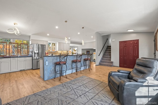 kitchen with decorative backsplash, stainless steel fridge, dark countertops, a kitchen breakfast bar, and open floor plan