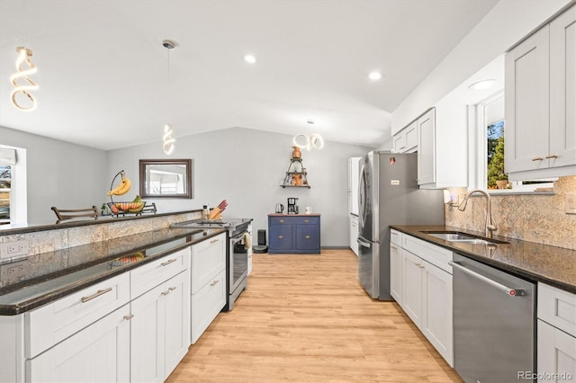 kitchen with a sink, decorative backsplash, vaulted ceiling, stainless steel appliances, and light wood-type flooring