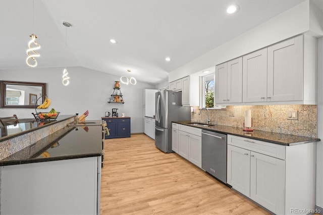 kitchen with tasteful backsplash, lofted ceiling, light wood-style flooring, appliances with stainless steel finishes, and a sink