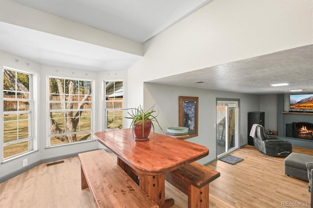 dining room with light wood-style floors, a fireplace, visible vents, and baseboards