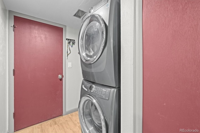 washroom featuring laundry area, stacked washer / dryer, and light wood-style flooring