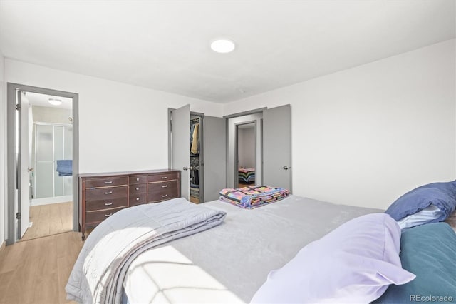 bedroom with light wood-type flooring, a closet, connected bathroom, and a spacious closet