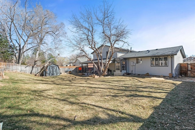 rear view of house with a storage shed, a yard, an outbuilding, and a fenced backyard