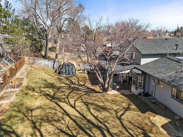 view of yard featuring an outdoor structure, a garden, fence, and a shed