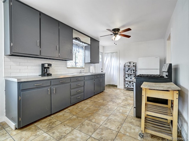 675 S Quivas St, Denver, CO 80223 - kitchen featuring decorative backsplash, ceiling fan, gas stove, baseboards, and freestanding refrigerator