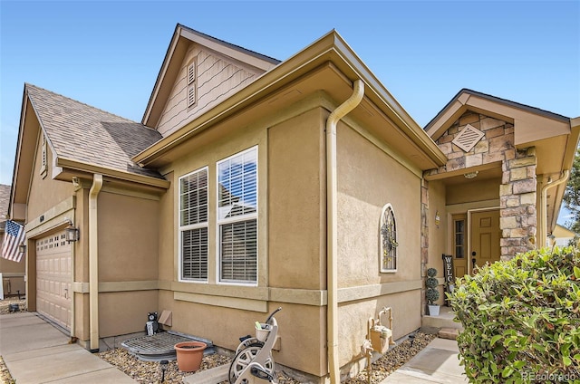 view of home's exterior featuring a garage, stucco siding, roof with shingles, stone siding, and driveway