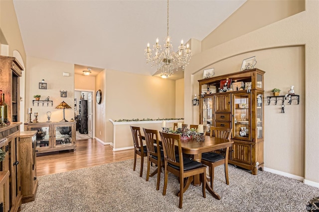 dining area with carpet floors, lofted ceiling, a chandelier, and baseboards