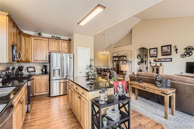 kitchen with stainless steel appliances, open floor plan, a chandelier, light wood-type flooring, and vaulted ceiling