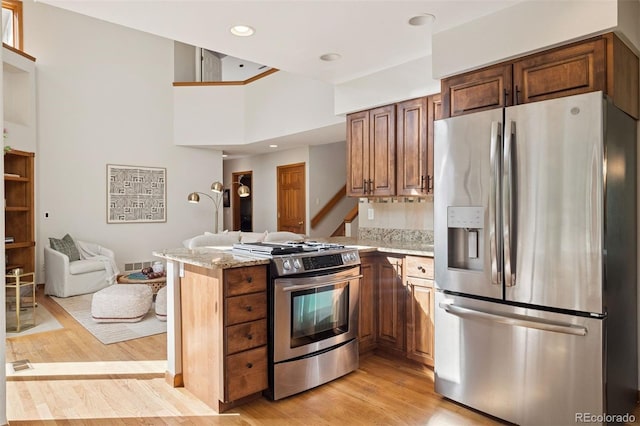 31402 N Bermuda Dunes Dr, Evergreen, CO 80439 - kitchen with stainless steel appliances, a peninsula, light wood-type flooring, open floor plan, and light stone counters