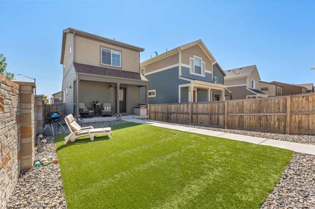 rear view of property featuring a yard, a patio, and a fenced backyard