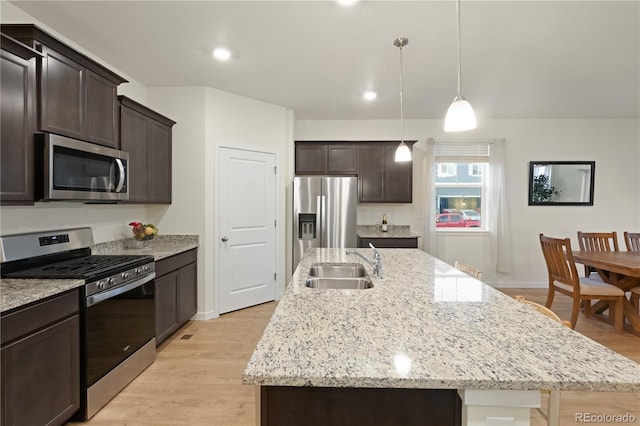 kitchen featuring appliances with stainless steel finishes, sink, light hardwood / wood-style flooring, and an island with sink