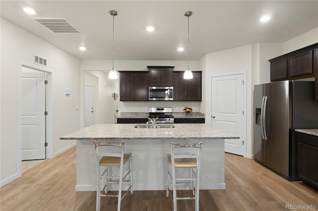 kitchen with dark brown cabinetry, an island with sink, appliances with stainless steel finishes, and light wood-type flooring