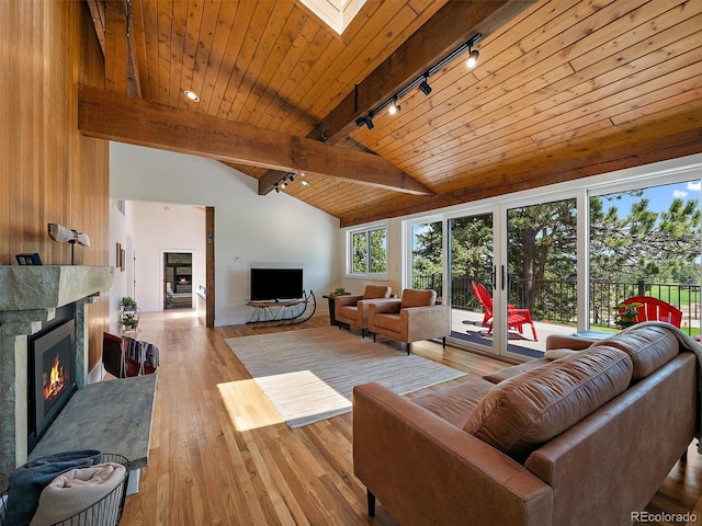 31756 Buffalo Park Rd, Evergreen, CO 80439 - living room featuring track lighting, a fireplace, wooden ceiling with exposed beams, a skylight, and wood finished floors