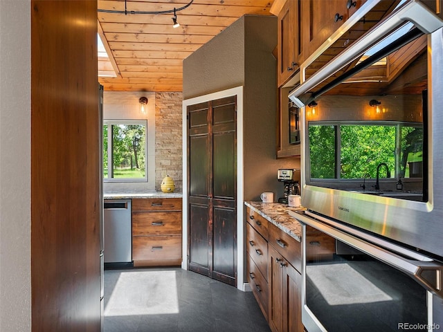31756 Buffalo Park Rd, Evergreen, CO 80439 - kitchen with stainless steel appliances, wooden ceiling, light stone countertops, brown cabinetry, and rail lighting