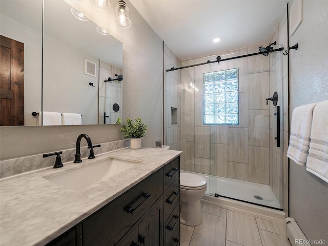 31756 Buffalo Park Rd, Evergreen, CO 80439 - bathroom with vanity, a shower stall, a baseboard radiator, toilet, and a textured wall