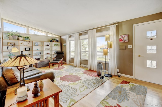 living room with vaulted ceiling, baseboards, and light wood-type flooring