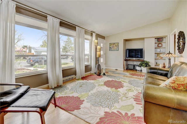 living room featuring vaulted ceiling, light wood-style flooring, built in shelves, and baseboards