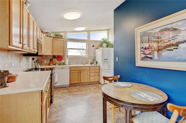 kitchen with white appliances, light brown cabinetry, light countertops, a sink, and tasteful backsplash