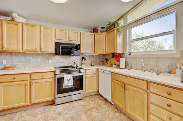 kitchen featuring stainless steel electric range oven, light brown cabinetry, dishwasher, and a sink