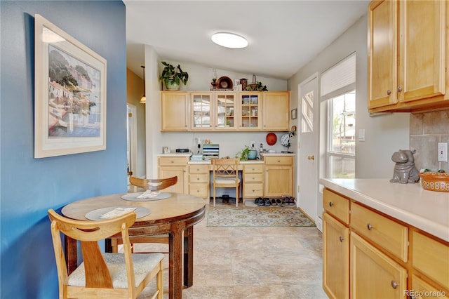 kitchen with light brown cabinets, vaulted ceiling, light countertops, and glass insert cabinets