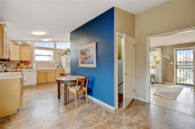 kitchen featuring dishwasher, light brown cabinetry, light countertops, and plenty of natural light