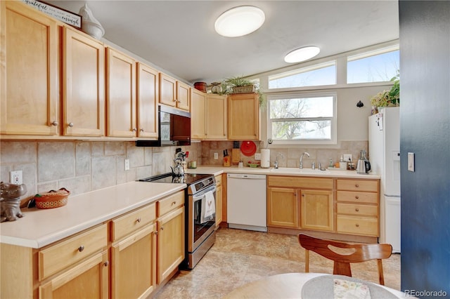 kitchen with white appliances, a sink, backsplash, and light countertops