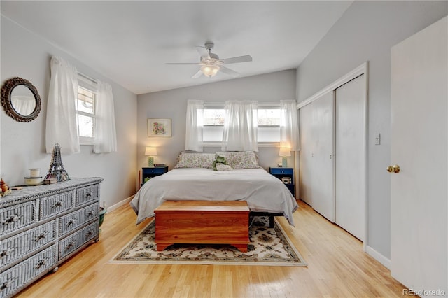 bedroom featuring multiple windows, wood finished floors, lofted ceiling, and a closet