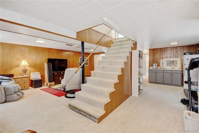 finished basement with wood walls, carpet flooring, and stairs