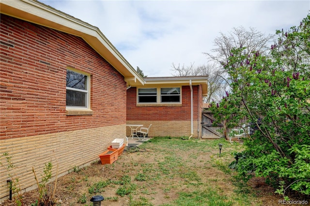view of home's exterior with brick siding, a gate, and fence