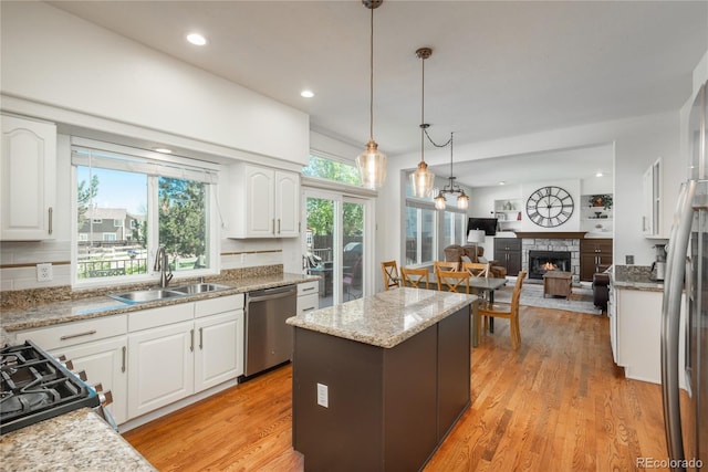 kitchen with dishwasher, a sink, a fireplace, a center island, and open floor plan