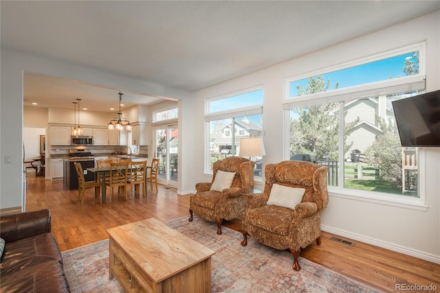 living area featuring a chandelier, wood finished floors, and baseboards