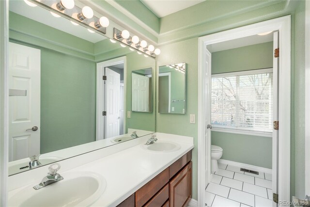 bathroom with tile patterned flooring, double vanity, toilet, and baseboards