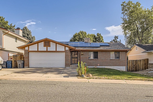 view of front of property featuring roof mounted solar panels, brick siding, fence, and an attached garage