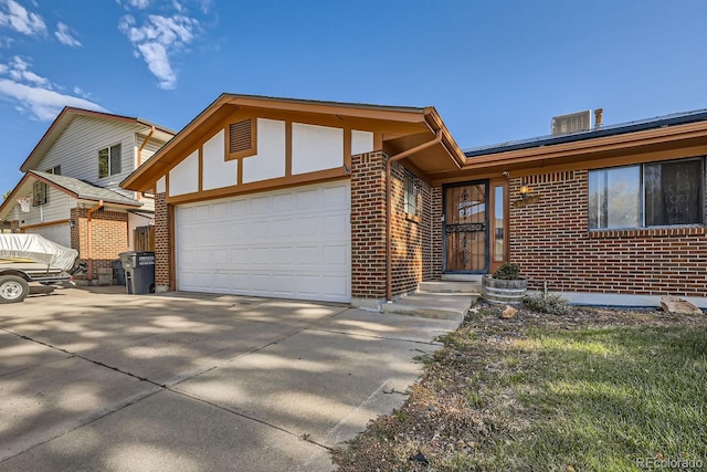 view of front of property featuring a garage, concrete driveway, and brick siding