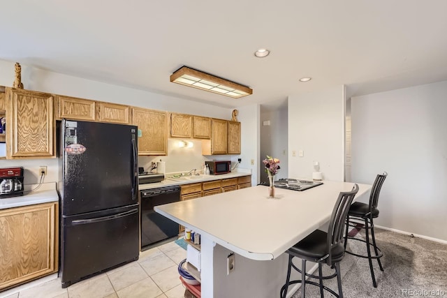 kitchen with light tile patterned floors, a sink, light countertops, black appliances, and a kitchen bar