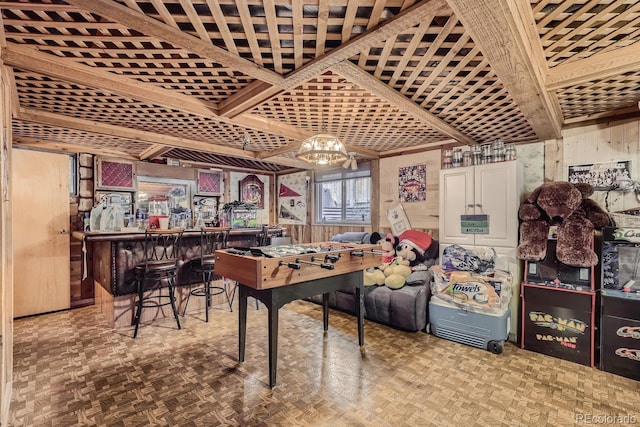 rec room with a dry bar, an inviting chandelier, and wooden walls