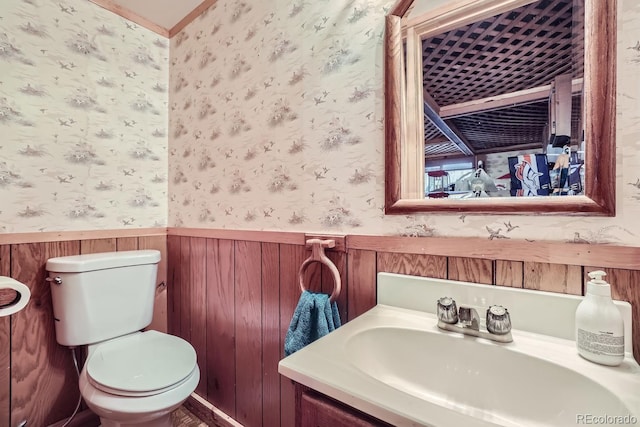 bathroom featuring wainscoting, vanity, toilet, and wallpapered walls