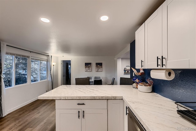 kitchen featuring kitchen peninsula, light stone countertops, white cabinets, and light wood-type flooring