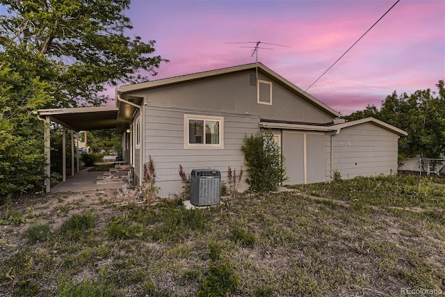 back house at dusk featuring central AC