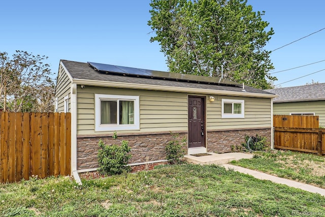 7101 E 66th Ave, Commerce City, CO 80022 - bungalow-style house with stone siding, solar panels, and a shingled roof