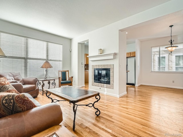 living room featuring a tile fireplace and light wood-type flooring