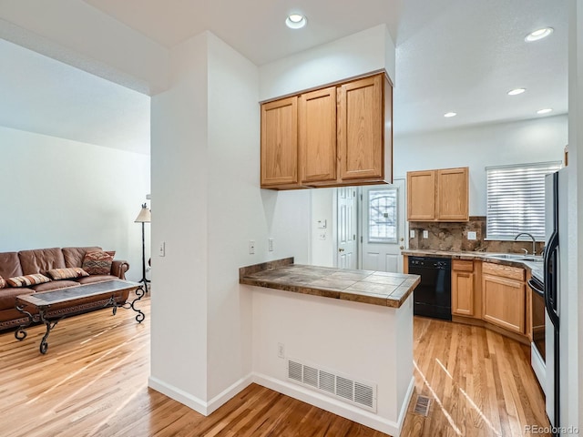 kitchen featuring backsplash, dishwasher, light hardwood / wood-style floors, and sink