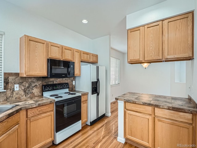 kitchen with light brown cabinets, white appliances, tasteful backsplash, and light hardwood / wood-style floors